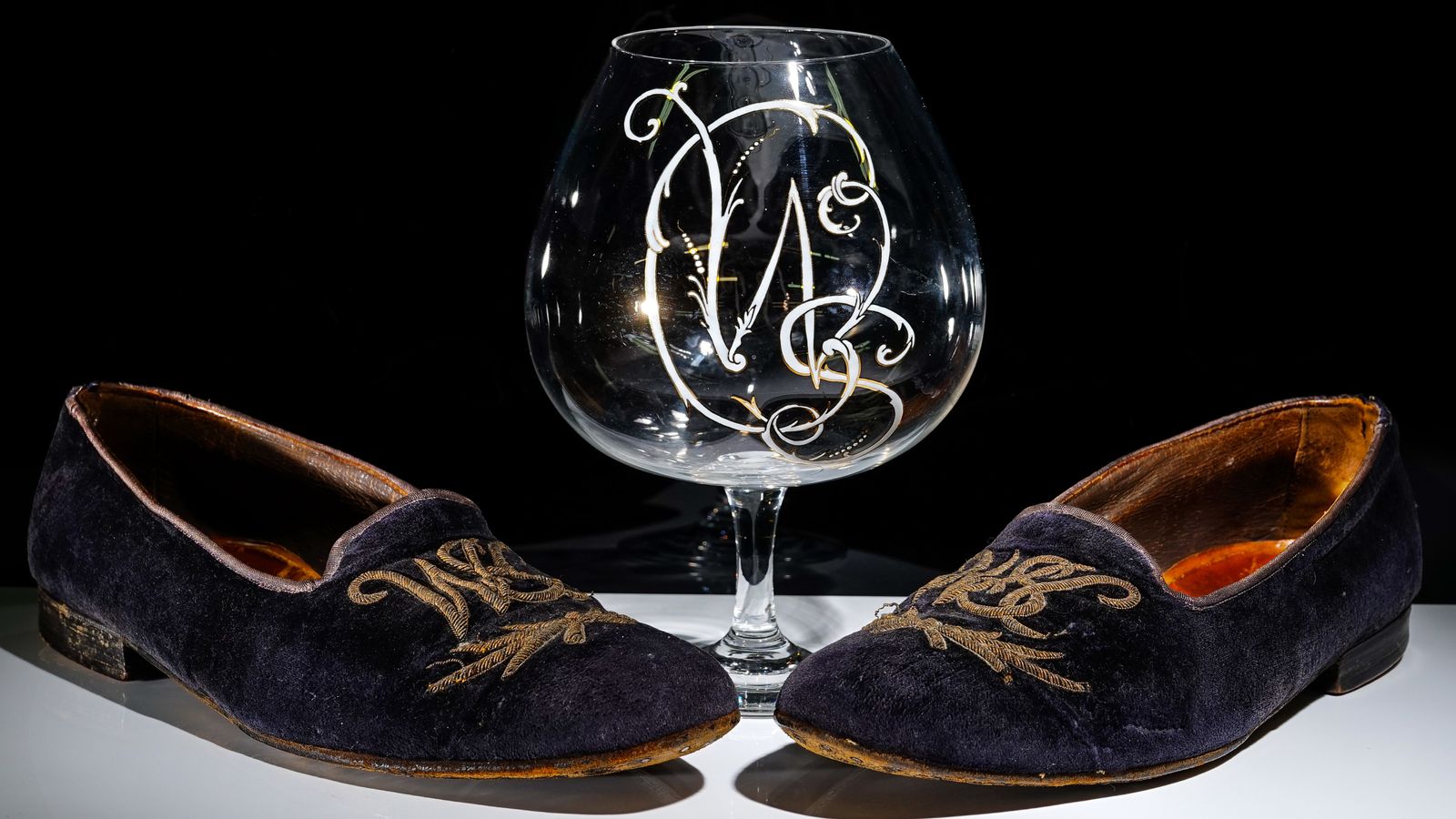 桌上的一副眼镜：天鹅绒拖鞋和白兰地玻璃各带有丘吉尔的名字首字母
